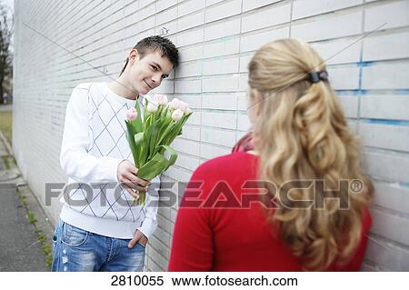 Stock Photography - Teenage boy giving flowers to his girlfriends . Fotosearch