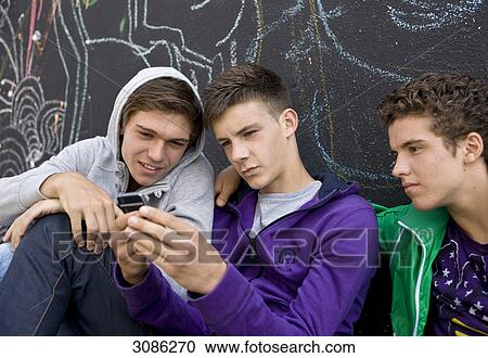 Stock Image - Three boys looking at a mobile phone, close-up . Fotosearch