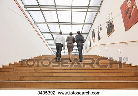 Three business people going upstairs View Large Photo Image Stock Image - Three business people going upstairs . Fotosearch