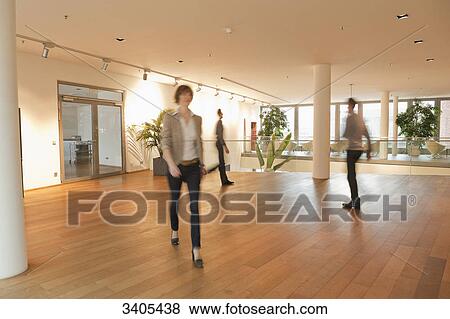 Three business people walking in office building View Large Photo Image Stock Photo - Three business people walking in office building . Fotosearch