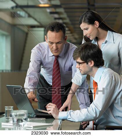 Three businesspeople looking at laptop in office View Large Photo Image Stock Image - Three businesspeople looking at laptop in office . Fotosearch