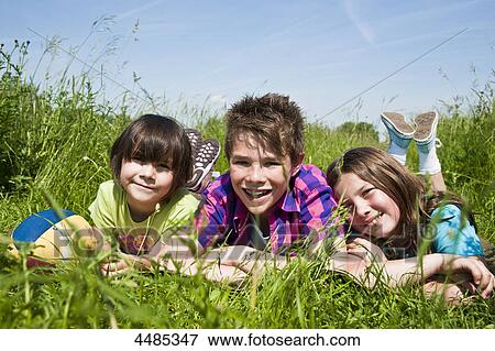 Three children lying on a meadow View Large Photo Image Stock Photo - Three children lying on a meadow . Fotosearch