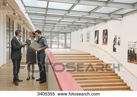 Three people standing in office building View Large Photo Image Stock Photography - Three people standing in office building . Fotosearch