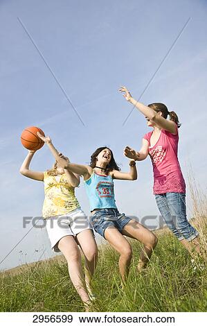 Three young girls are playing on a meadow with a Ball, low angle view View Large Photo Image Stock Photo - Three young girls are playing on a meadow with a Ball, low angle view . Fotosearch