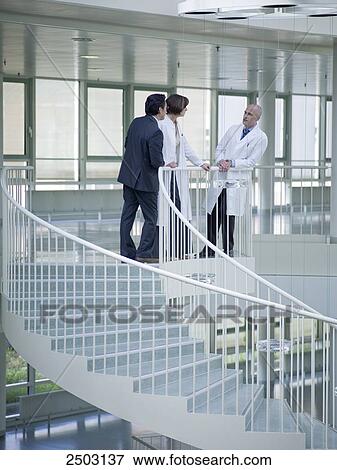 Stock Photo - Two doctors and businessman discussing . Fotosearch