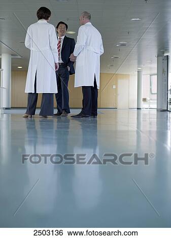 Stock Photograph - Two doctors discussing with businessman . Fotosearch