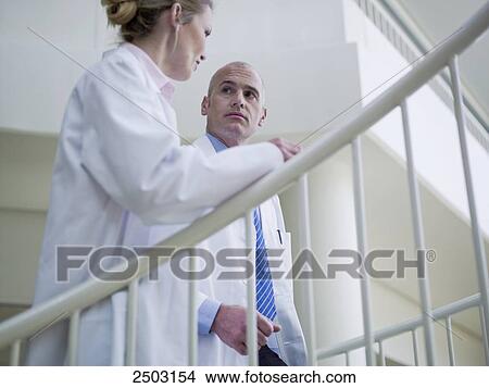 Picture - Two doctors moving up on staircase . Fotosearch