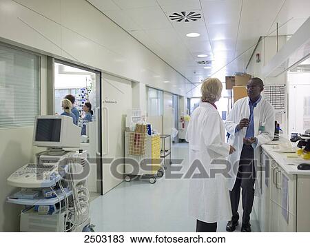 Stock Image - Two doctors standing in corridor of hospital . Fotosearch