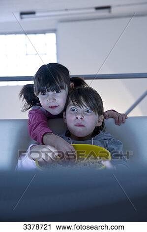 Two girls watching TV and eating popcorn, front view View Large Photo Image Stock Image - Two girls watching TV and eating popcorn, front view . Fotosearch