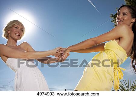 Stock Image - Two happy young women under blue sky . Fotosearch