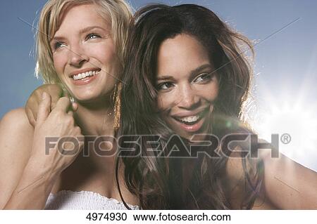 Stock Image - Two happy young women under blue sky . Fotosearch