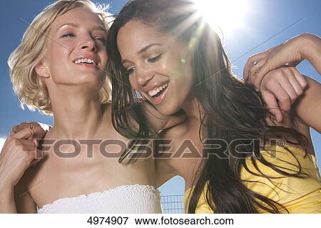 Two happy young women under blue sky View Large Photo Image Stock Photo - Two happy young women under blue sky . Fotosearch