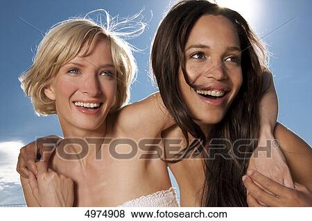 Two happy young women under blue sky View Large Photo Image Stock Photo - Two happy young women under blue sky . Fotosearch