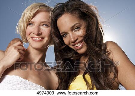 Two happy young women under blue sky View Large Photo Image Stock Photo - Two happy young women under blue sky . Fotosearch