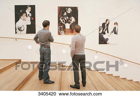 Two men looking at photos on wall View Large Photo Image Stock Image - Two men looking at photos on wall . Fotosearch