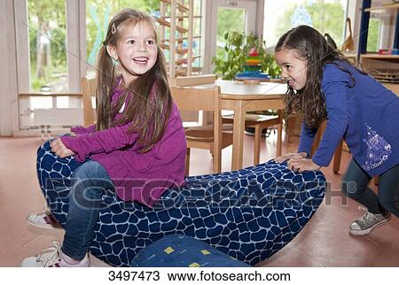 Two young girls playing with a seesaw View Large Photo Image Stock Image - Two young girls playing with a seesaw . Fotosearch