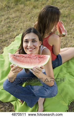 Two young women eating melons outdoors View Large Photo Image Stock Image - Two young women eating melons outdoors . Fotosearch