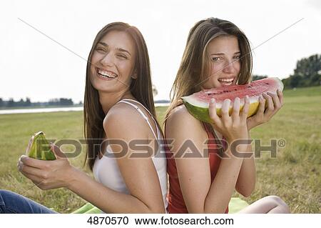 Two young women eating melons outdoors View Large Photo Image Stock Image - Two young women eating melons outdoors . Fotosearch
