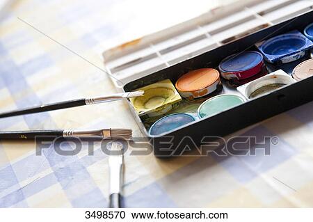 Stock Image - Watercolours and paint brushes on a table, close-up . Fotosearch