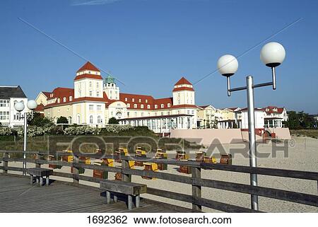 Stock Image - Wicker beach chairs on beach with hotel in background . Fotosearch
