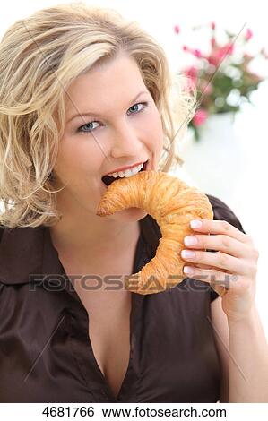 Stock Photograph - Woman eating croissant . Fotosearch