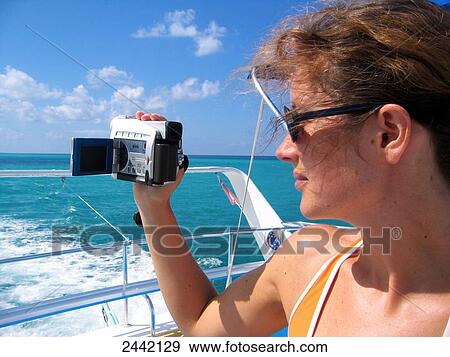 Stock Photo - Woman filming sea with home video camera . Fotosearch