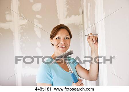 Woman hammering nail into wall View Large Photo Image Stock Image - Woman hammering nail into wall . Fotosearch
