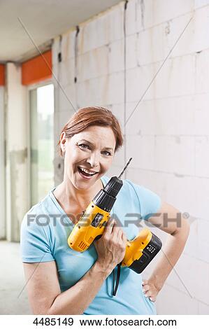 Stock Photo - Woman holding drill machine . Fotosearch