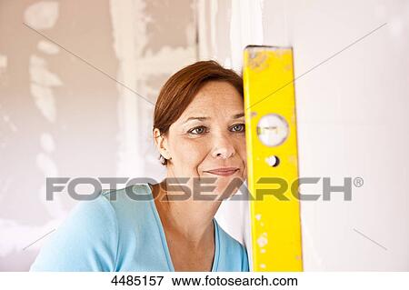 Woman holding level at wall View Large Photo Image Stock Photo - Woman holding level at wall . Fotosearch