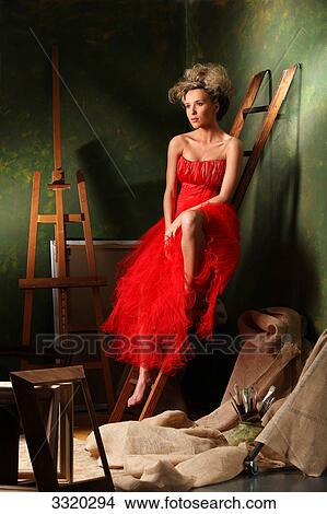 Picture - Woman in a red dress sitting on a ladder . Fotosearch