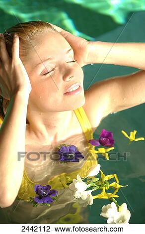 Stock Image - Woman in swimming pool with flowers . Fotosearch