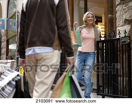 Woman looking at man carrying shopping bags View Large Photo Image Stock Image - Woman looking at man carrying shopping bags . Fotosearch
