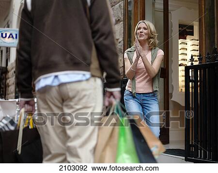 Woman looking at man carrying shopping bags View Large Photo Image Stock Image - Woman looking at man carrying shopping bags . Fotosearch