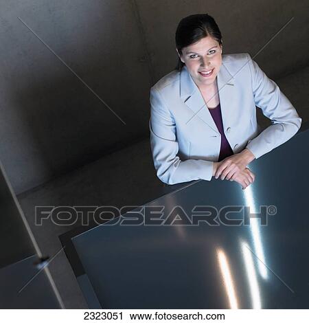Stock Image - Woman sitting at table and smiling . Fotosearch