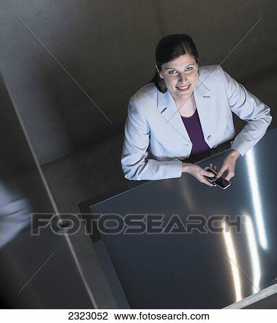 Stock Image - Woman sitting at table using mobile phone . Fotosearch