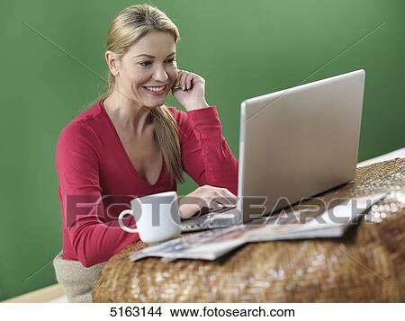 Woman sitting in front of laptop View Large Photo Image Picture - Woman sitting in front of laptop . Fotosearch