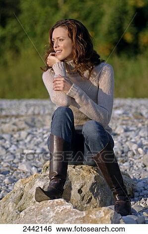 Woman sitting on rock and smiling View Large Photo Image Stock Photograph - Woman sitting on rock and smiling . Fotosearch