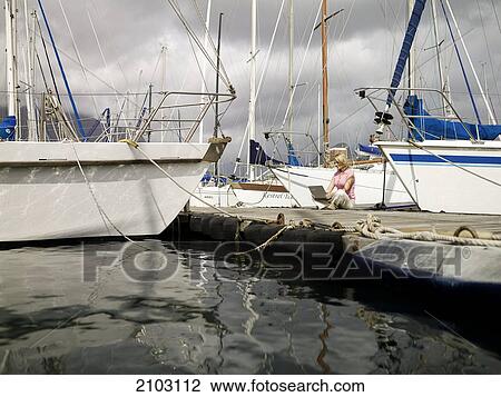 Stock Image - Woman using laptop at harbor . Fotosearch