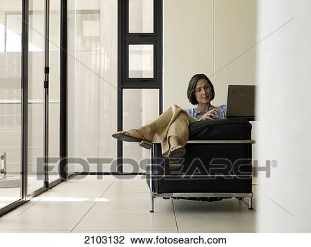 Stock Image - Woman using laptop on couch . Fotosearch