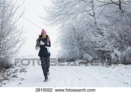 Stock Image - Woman walking in snow covered landscape . Fotosearch