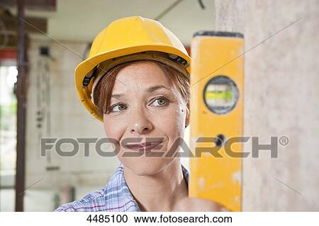 Stock Image - Woman with level and helmet . Fotosearch