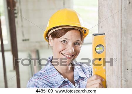 Woman with level and helmet View Large Photo Image Stock Photo - Woman with level and helmet . Fotosearch