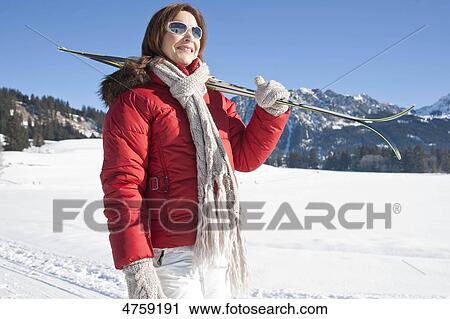 Stock Image - Woman with skis in winter landscape, Tannheimer Tal, Tyrol, Austria . Fotosearch