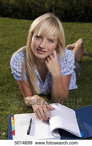 Young blond woman lying in grass with file folder View Large Photo Image Stock Photo - Young blond woman lying in grass with file folder . Fotosearch