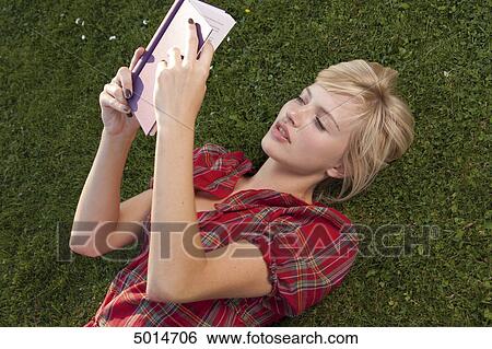 Young blond woman reading book in grass View Large Photo Image Stock Photograph - Young blond woman reading book in grass . Fotosearch