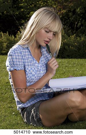 Young blond woman sitting in grass with file folder View Large Photo Image Stock Image - Young blond woman sitting in grass with file folder . Fotosearch
