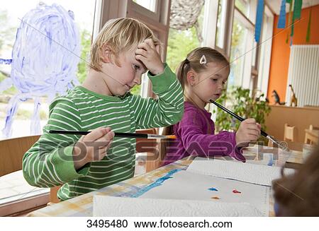 Stock Image - Young boy and girl painting in the kindergarten . Fotosearch