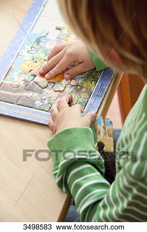 Young boy doing a jigsaw, elevated view View Large Photo Image Stock Image - Young boy doing a jigsaw, elevated view . Fotosearch