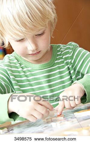 Young boy doing a jigsaw, low angle view View Large Photo Image Stock Photography - Young boy doing a jigsaw, low angle view . Fotosearch