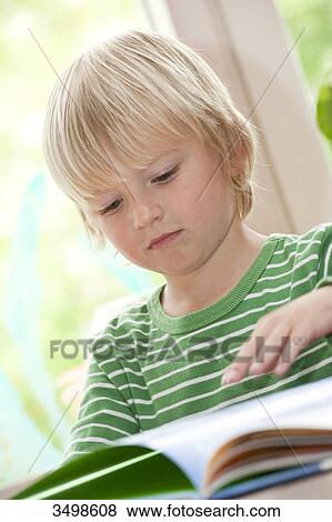 Stock Photo - Young boy looking at a book, low angle view . Fotosearch